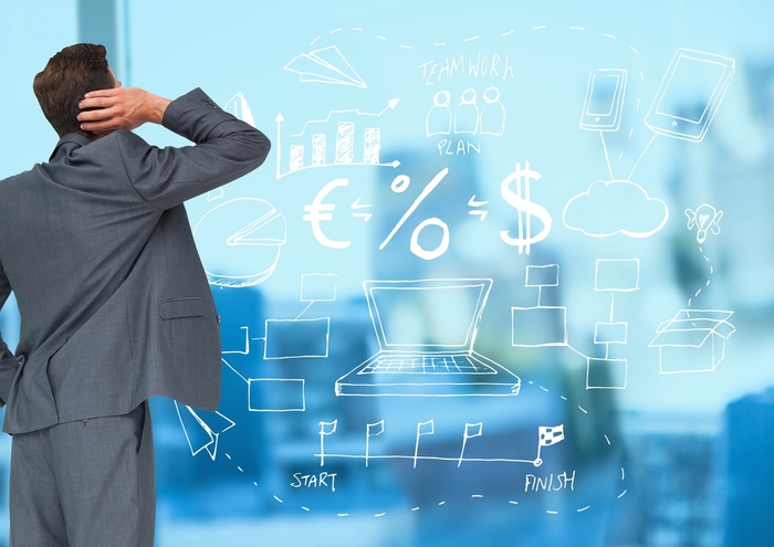 Rear view of a businessman looking at business related graphics on a glass wall