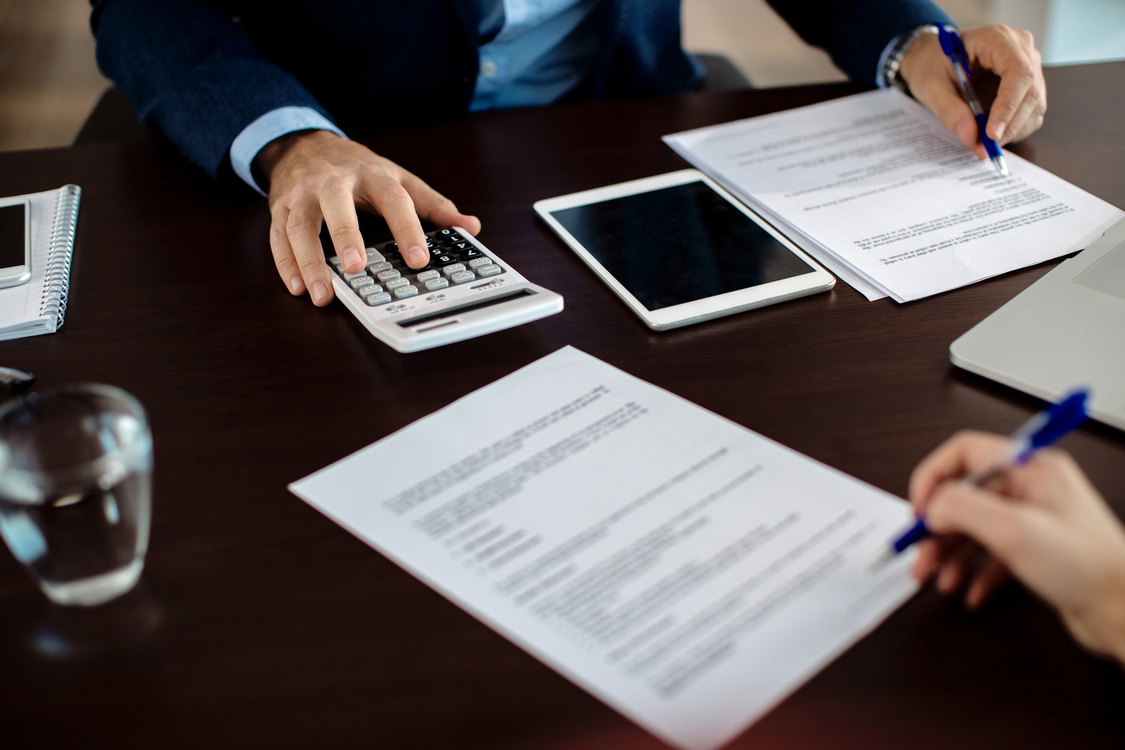Close up of financial consultant going through paperwork on a me